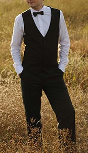 Groom In a vested suit posing in the field